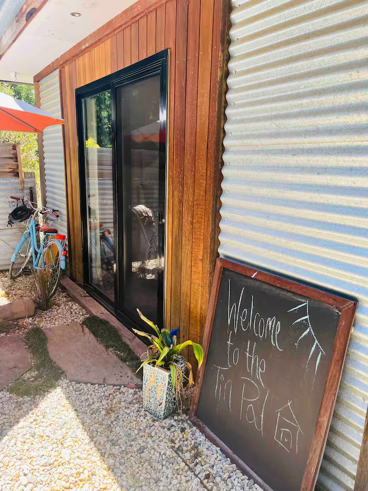 Welcome to The Tin Pod — entry with chalkboard and bike